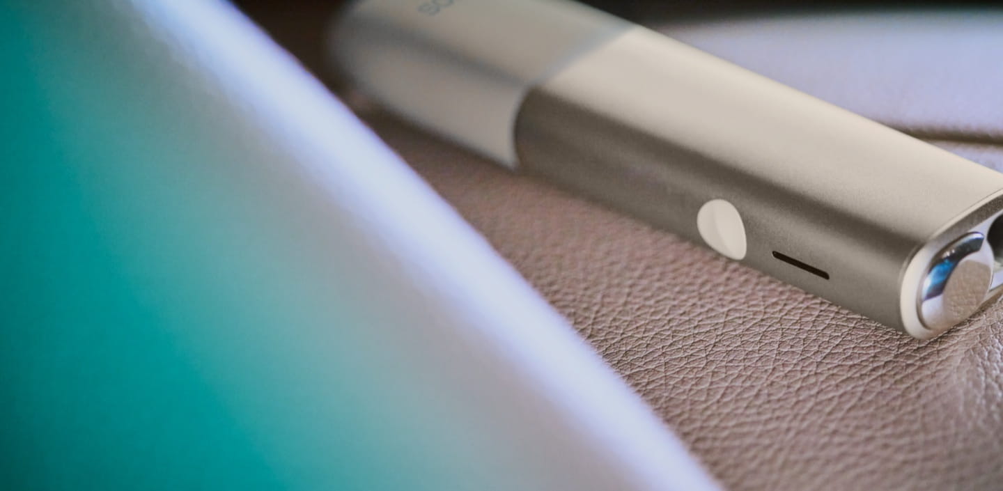 جهاز IQOS ILUMA ONE على سطح جلدي.